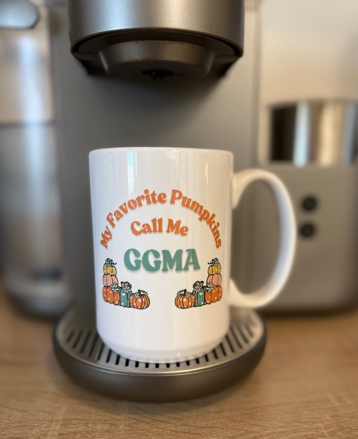 White mug with text and pumpkin graphics in front of a coffee maker